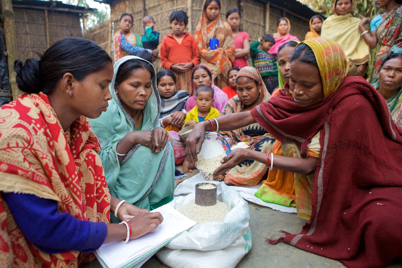 hero-img-01 Village women in Bangladesh gather for community development planning and resource distribution.